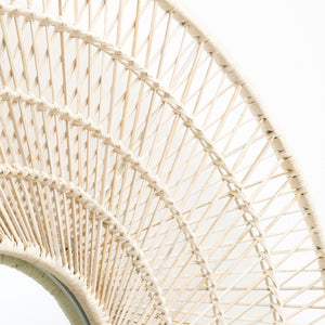 Close-up of the Made Goods Saffron Mirror reveals its '70s-inspired woven rattan frame with curved, intersecting lines in natural beige, showcased against a plain white background.