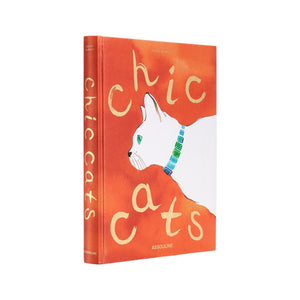Assouline’s "Chic Cats" is a hardcover book featuring a white cat with a green collar on an orange cover, celebrating cat-inspired artwork and feline art.
