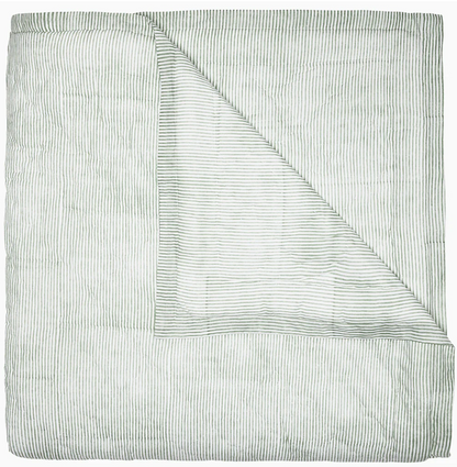 Expertly hand quilted from soft cotton voile, the Nandi Bedding Collection by John Robshaw features a folded light quilt with thin, horizontal green stripes and a corner turned down to reveal an underside with matching stripes, offering a lightweight and luxurious feel.
