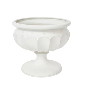 The Juliska Large Whitewashed Decorative Urn features a pedestal design with scalloped patterns and circular accents, making it an elegant centerpiece or a stylish addition to your formal garden décor.