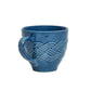 Le Panier Mystic Knot Denim mug by Juliska, featuring a textured braided pattern encircling the body and handle, photographed on a plain white background.
