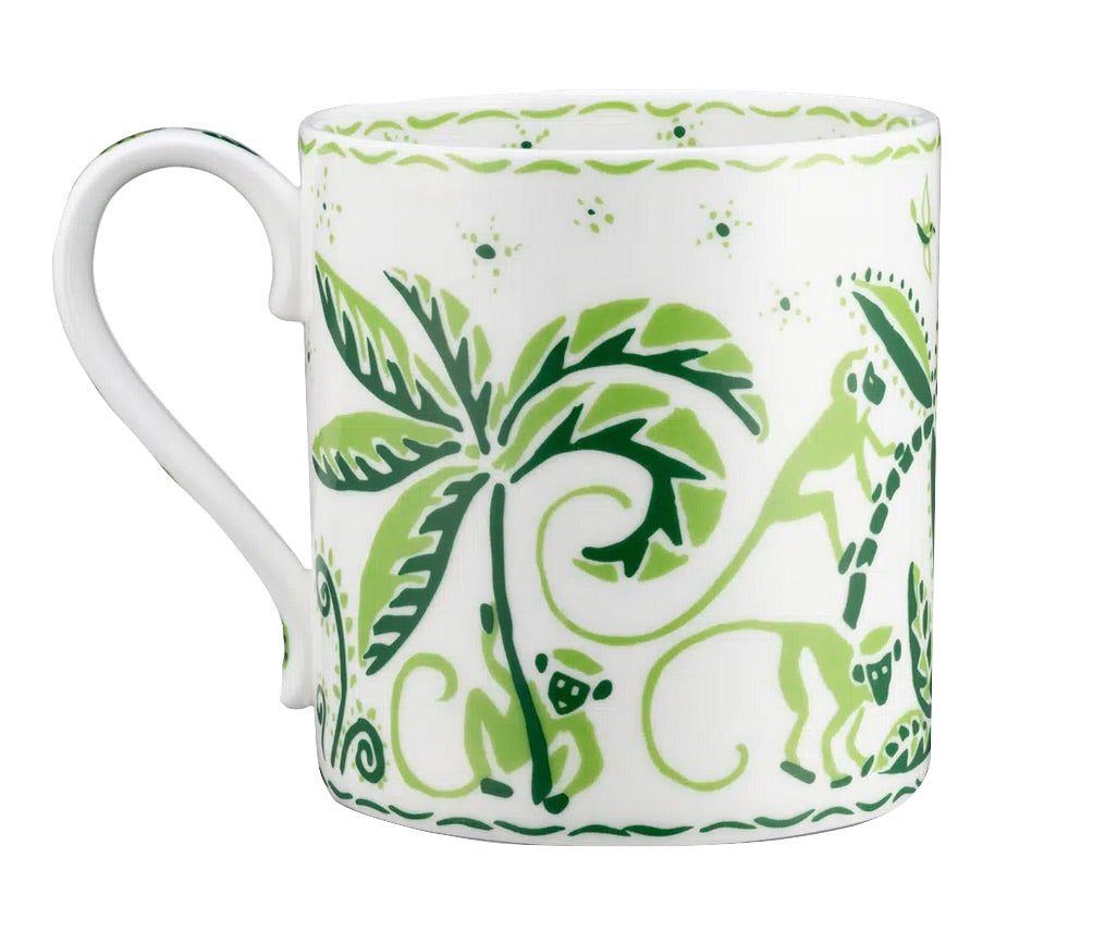 The Cobblers Cove Calypso Dinnerware Collection by Royal Crown Derby features a white ceramic mug adorned with playful green monkeys, palm trees, and foliage for a vibrant Caribbean touch.