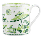 Part of the Cobblers Cove Calypso Dinnerware Collection by Royal Crown Derby, this white ceramic mug features a vibrant green design with a beach umbrella, turtle, fish, sun, and plants to evoke a Caribbean atmosphere.
