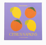 Square purple box from Piecework’s Cocktail Napkin Collection, featuring illustrations of two lemons and two oranges on the lid—perfect for gifting linen cocktail napkins or adding style to your favorite napkin sets.
