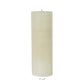 A Perin Mowen Solid Pillar Candle Collection piece—a tall white beeswax candle (3" diameter, 9" height)—is shown against a plain white background, showcasing the warm glow of natural candlelight.