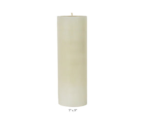 A Perin Mowen Solid Pillar Candle Collection piece—a tall white beeswax candle (3" diameter, 9" height)—is shown against a plain white background, showcasing the warm glow of natural candlelight.
