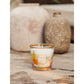 A Baobab Collection Saint Tropez candle by Baobab in a glass holder with orange accents infuses the air with a summery scent, while two textured vases in the background enhance the decor.