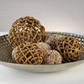 The Zodax Water Hyacinth Twisted Fill Ball Collection features decorative spheres in a silver bowl, perfect for adding natural woven style to your home or garden décor.