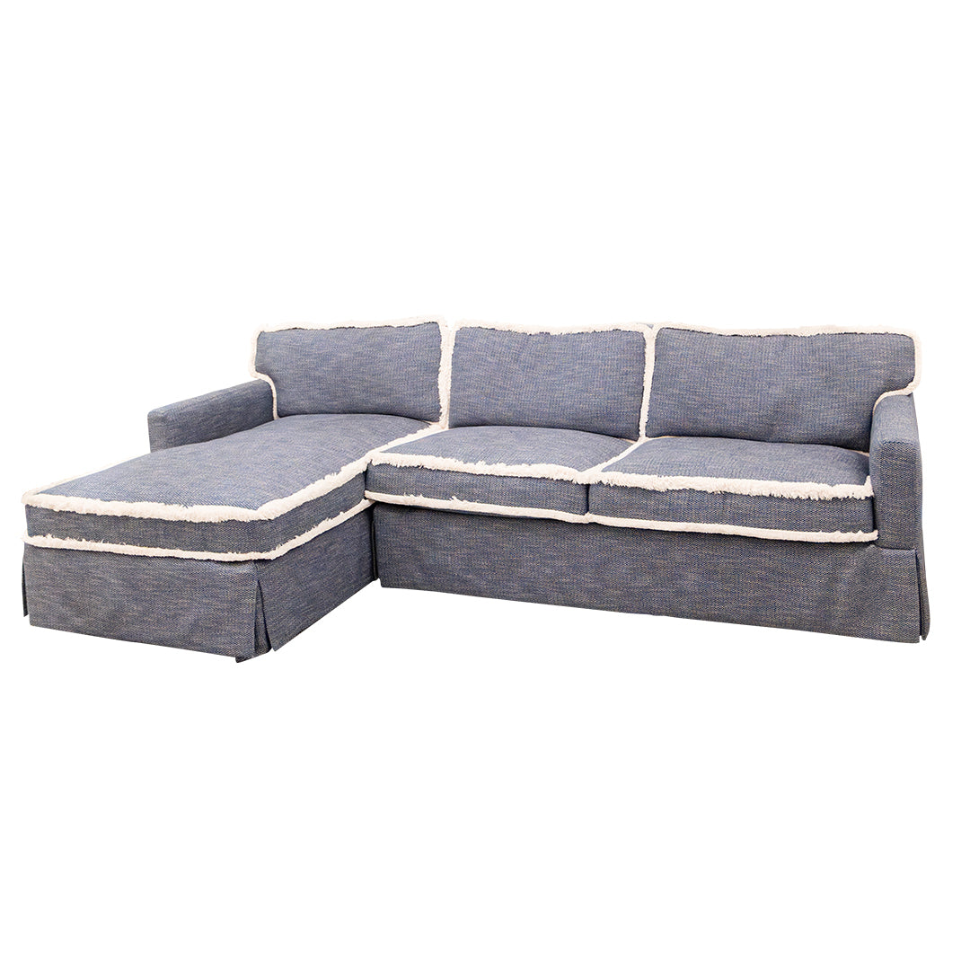 The 2-Piece Sectional in Denim by Lee Industries features an L-shaped design with three seat cushions, a left-side chaise lounge, and distinctive white trim accenting the cushion and backrest edges. Its modular construction allows for flexible arrangement to fit a variety of living spaces.