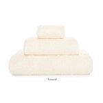 Three neatly folded towels from the Graccioza Egoist Bath Collection, in off-white and assorted sizes, are stacked against a white background. Made from high density textile, "Natural" appears beneath the stack.