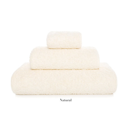 Three neatly folded towels from the Graccioza Egoist Bath Collection, in off-white and assorted sizes, are stacked against a white background. Made from high density textile, "Natural" appears beneath the stack.