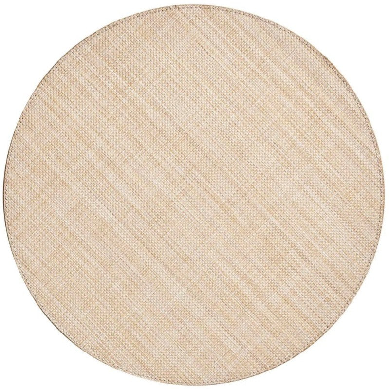 The Kim Seybert Portofino Placemat is a round, beige woven vinyl placemat with a subtle diagonal pattern, shown on a white background for an easy-to-clean surface.