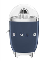 A blue SMEG Citrus Juicer from the Smeg brand has a chrome finish, transparent lid, and logo on the front. Made of die-cast aluminum, it features an anti-drip spout for mess-free juicing.