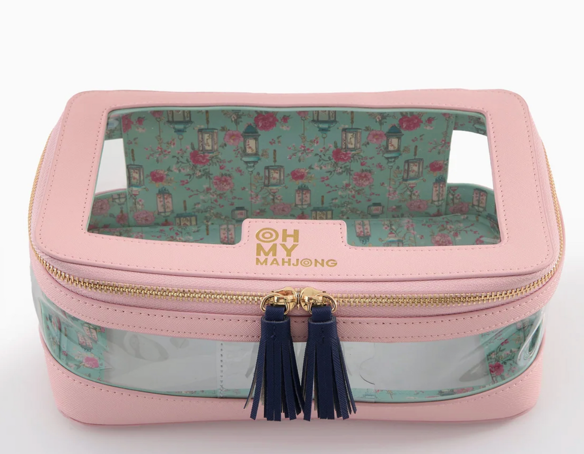 An Oh My Mahjong Tile Storage Bag in pink, featuring a rectangular shape, clear top and front, floral pattern lining, and navy blue tassel zipper pulls.
