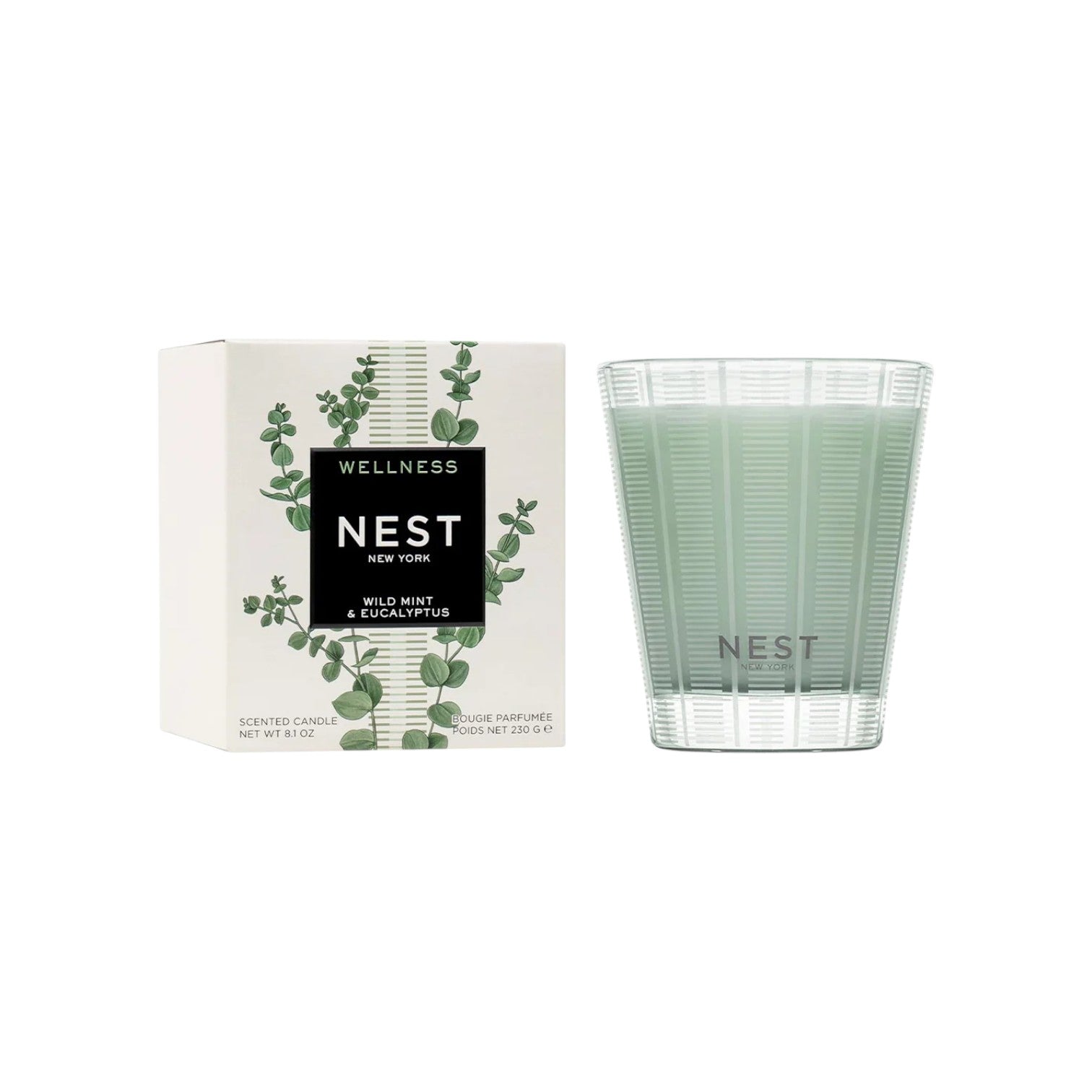A Nest Wild Mint & Eucalyptus Candle from the Candle Collection is displayed beside its box, featuring eucalyptus leaf decor. The light green wax sits in a clear glass holder, capturing the candle's fresh, invigorating scent.