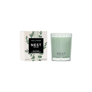 A Nest Wild Mint & Eucalyptus Candle from the Candle Collection sits beside its box, which displays a botanical design—an ideal choice for any scented candle lover.