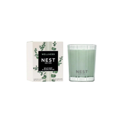 A Nest Wild Mint & Eucalyptus Candle from the Candle Collection sits beside its box, which displays a botanical design—an ideal choice for any scented candle lover.