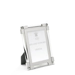 A nickel plated silver photo frame from the William Yeoward Crystal Clear Classic Frame Collection stands on a plain white background, displaying a card with the brand name. Its bright finish lends elegance to any classic photo display.