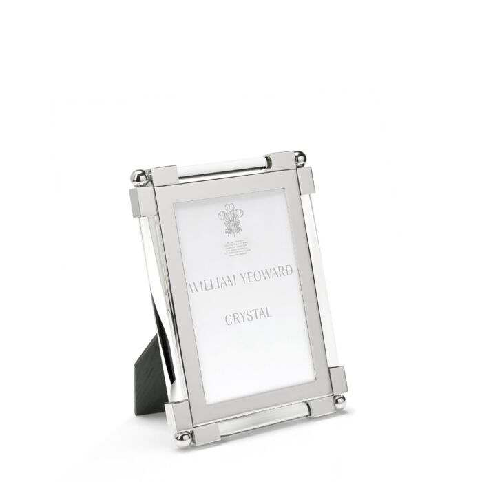 A nickel plated silver photo frame from the William Yeoward Crystal Clear Classic Frame Collection stands on a plain white background, displaying a card with the brand name. Its bright finish lends elegance to any classic photo display.