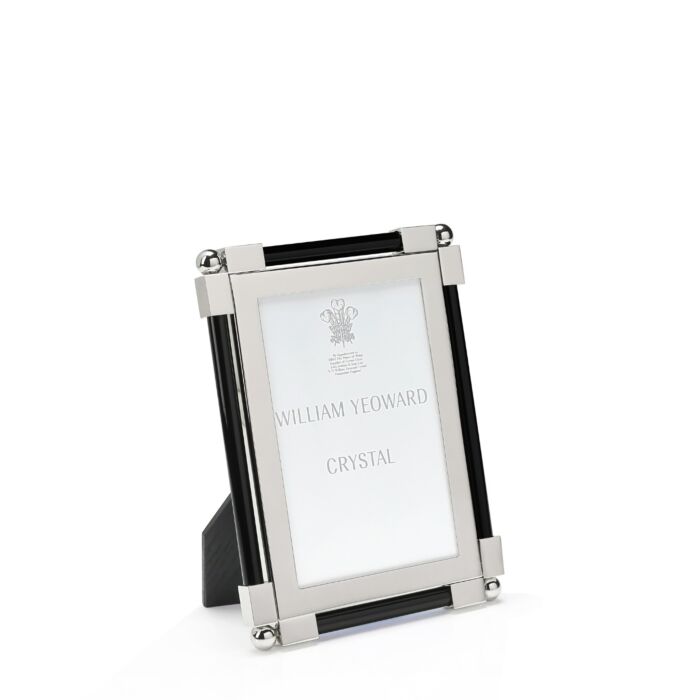 The Black Classic Frame Collection by William Yeoward Crystal features a rectangular nickel-plated metal and glass photo frame with black accents, standing upright. Its bright finish adds a modern touch, and the insert reads "William Yeoward Crystal.
