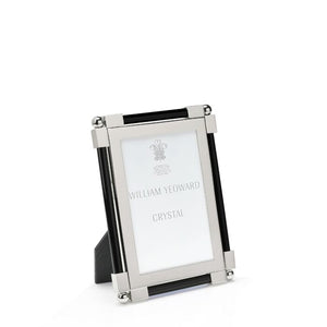 The Black Classic Frame Collection by William Yeoward Crystal features a rectangular nickel-plated metal and glass photo frame with black accents, standing upright. Its bright finish adds a modern touch, and the insert reads "William Yeoward Crystal.