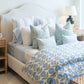 Lee Industries Dome Queen Bed featuring a tall, curved upholstered headboard, dressed in layered bedding with blue and white floral and striped patterns.