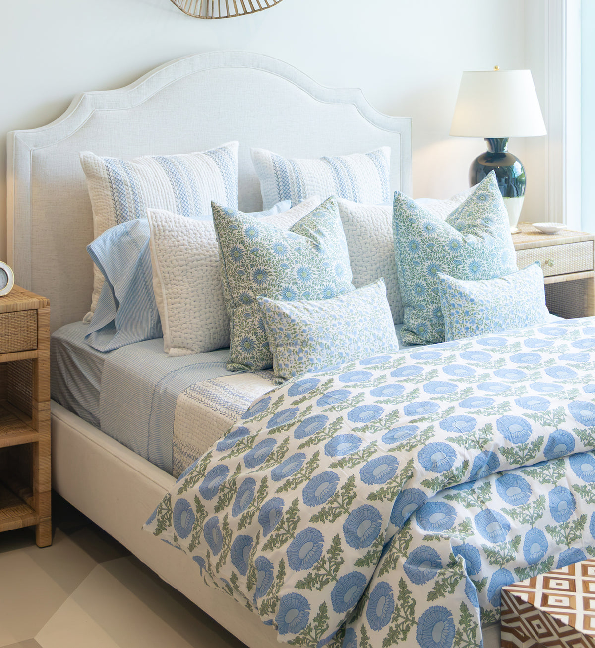 Lee Industries Dome Queen Bed featuring a tall, curved upholstered headboard, dressed in layered bedding with blue and white floral and striped patterns.