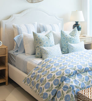 Lee Industries Dome Queen Bed featuring a tall, curved upholstered headboard, dressed in layered bedding with blue and white floral and striped patterns.