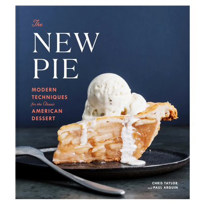 A slice of apple pie topped with melting vanilla ice cream rests on a black plate on the cover of The New Pie, a cookbook from Penguin Random House that highlights inventive pie recipes and creative baking techniques.