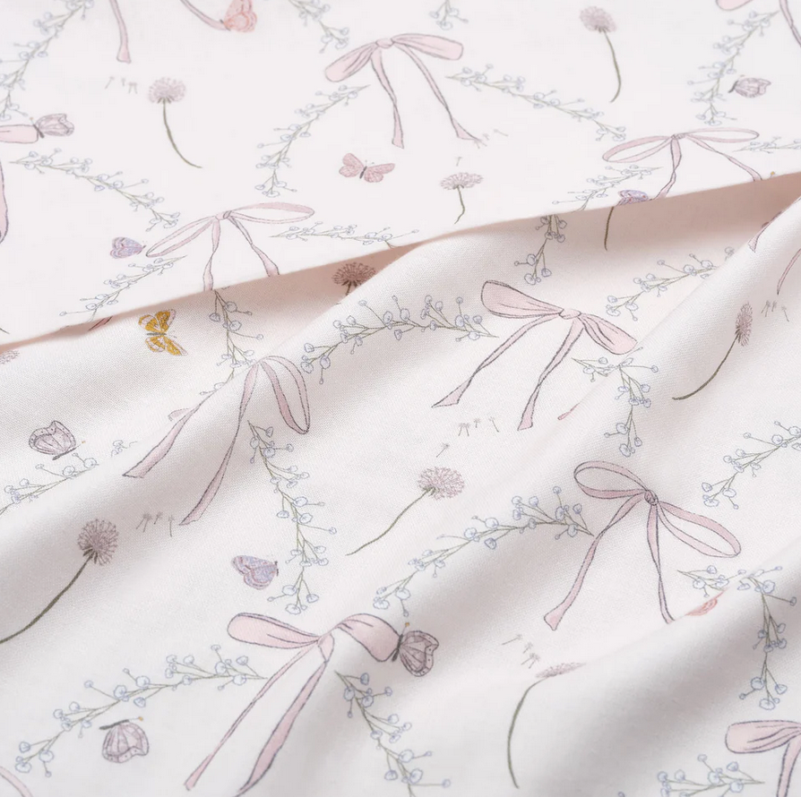 A close-up of the Gooselings Bows & Butterfly Kisses Swaddle, featuring soft pastel bows, flowers, and butterflies on 100% cotton—ideal for a cozy baby swaddle.
