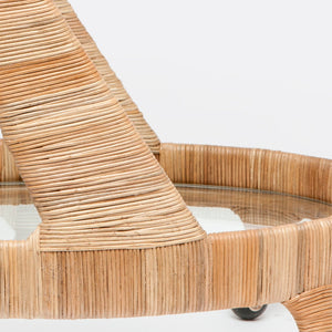 Close-up of the Lulu Retro Rattan Bar Cart by Made Goods, featuring a wicker table leg, rounded rim, and glass tabletop that highlights the tightly woven natural fibers.