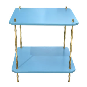 The Satin Lacquered Side Table by Two World Arts Group features two tiers, a light blue surface, and gold metal legs crafted to mimic bamboo stalks.
