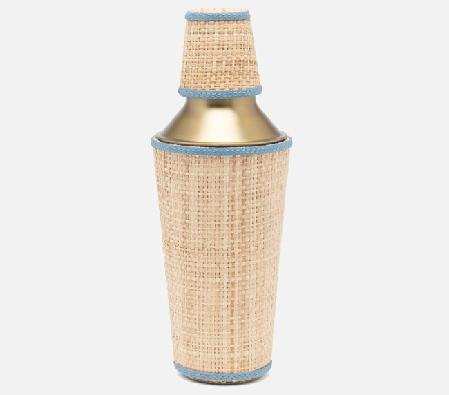 A metal cocktail shaker wrapped in rattan with blue leather trim from the Gable Natural/White Barware Collection by Blue Pheasant, shown on a white background.