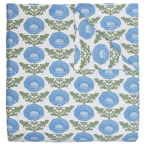 The Kaavia Light Indigo Bedding Collection by John Robshaw features a quilt adorned with a repeating pattern of large blue flowers and green leaves on a white background, evoking the timeless look of classic floral block prints. Shown with one corner folded to reveal the reverse side, this quilt is crafted from soft 200 thread count fabric for exceptional comfort and can also serve as a lightweight duvet for versatile layering.
