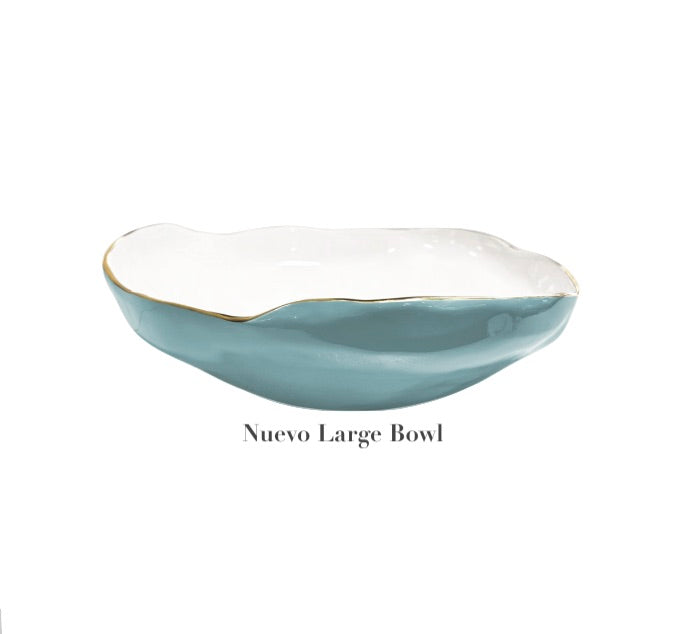 A large ceramic bowl from Beatriz Ball's Encanto Turquoise Serveware Collection featuring a wavy rim, blue exterior, white interior, and thin gold edge. "Nuevo Large Bowl" is displayed beneath the bowl.