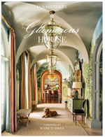 Book cover of "The Glamorous House" by Abrams shows an elegant hallway with arched ceilings, grand chandeliers, wall murals, refined furniture, and a dog—embodying the luxury interiors highlighted in the book.