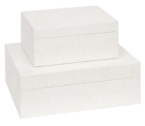 Two white, rectangular storage boxes of different sizes, reminiscent of delicate eggshells, are stacked on top of each other. The top box is the Della Box, Small by Made Goods.