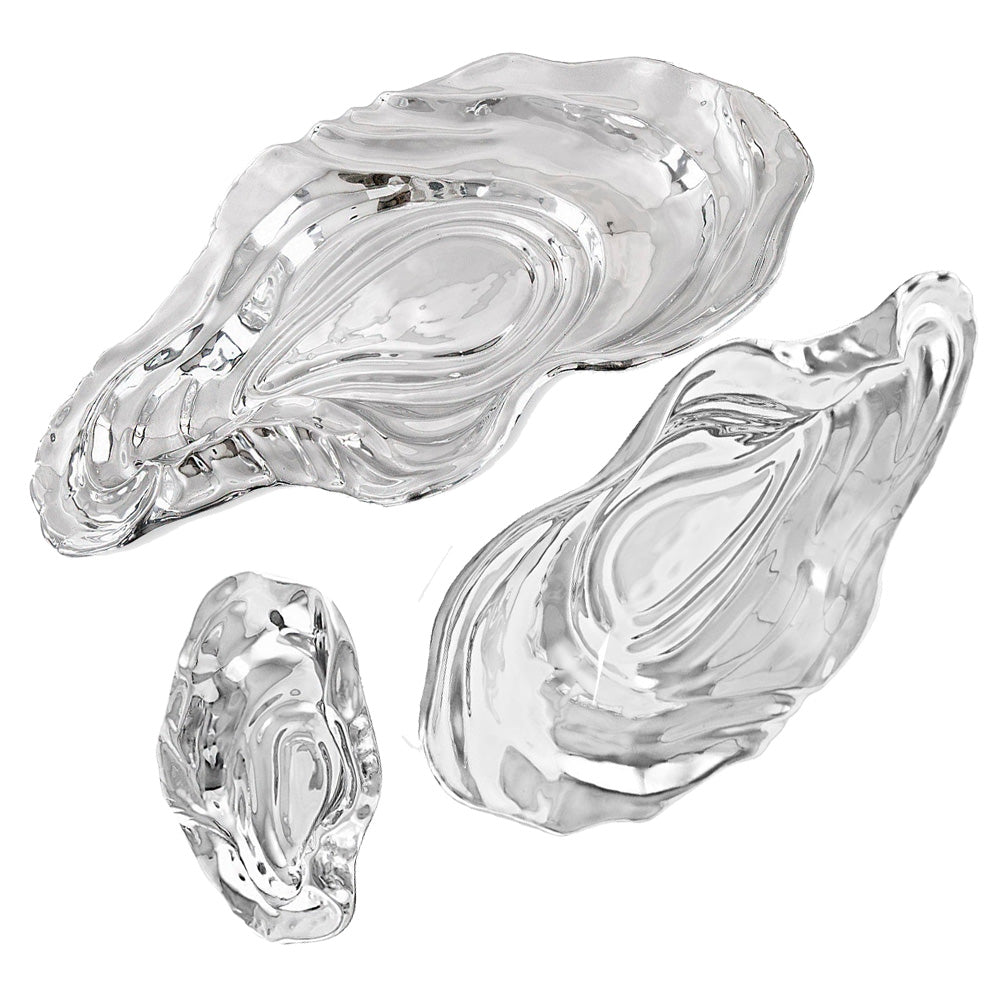 The Ocean Oyster Bowl Collection by Beatriz Ball features three clear glass dishes in varying sizes, inspired by oyster shell shapes and displayed on a white background.