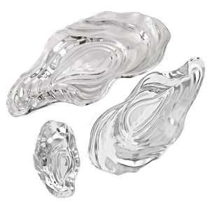 The Ocean Oyster Bowl Collection by Beatriz Ball features three clear glass dishes in varying sizes, inspired by oyster shell shapes and displayed on a white background.