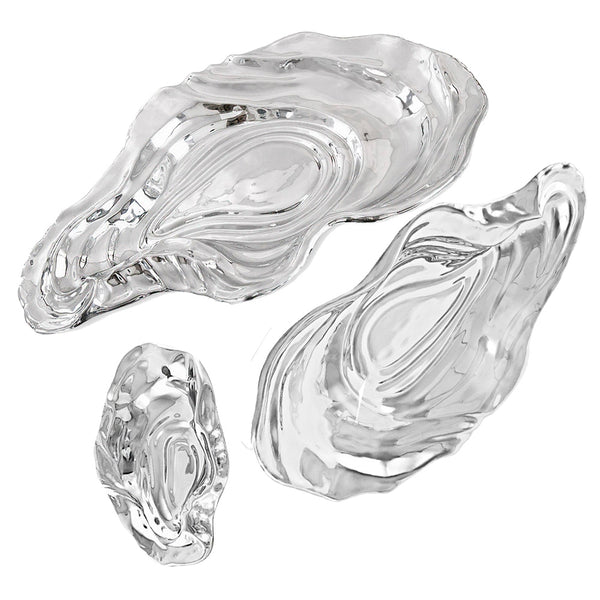 Three hand-polished metal bowls from the Beatriz Ball Ocean Oyster Bowl Collection, resembling oyster shells, arranged on a white background.