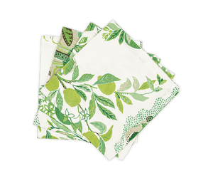 Set of four folded linen cloth napkins from the Citrus Garden Grass Collection by Matouk, featuring Schumacher's fresh green botanicals and bright citrus fruit on a crisp white background.