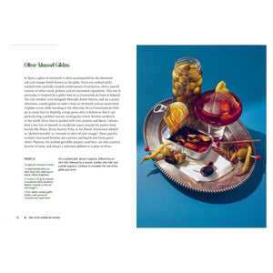 A silver tray with vermouth, green olives, mussels, toothpicks, lemon slice & snail shell—ideal for olive recipes. Recipe from The Little Book of Olives by Abrams shown on the left.