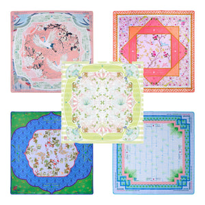 Five vibrant square scarves from the Oh My Mahjong Mahjong Mat Collection, each with ornate floral and geometric designs and a non-slip surface inspired by Mahjong mats, are arranged in a grid on a white background.
