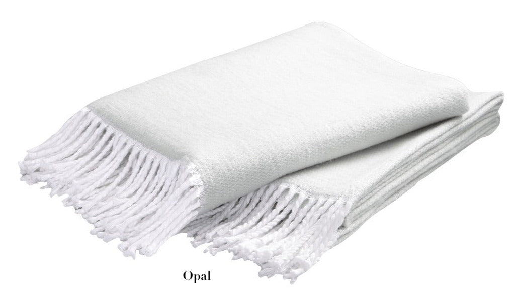 A folded white Pezzo Throw from Matouk, shown with fringe against a plain background. Made from brushed cotton and OEKO-TEX certified, this cozy blanket adds comfort and style to any space.