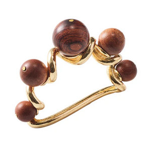 The Kim Seybert Bois Napkin Ring in Brown/Gold features a wavy gold band topped with five round brown wooden beads, creating a hand-crafted, uniquely charming table accent.