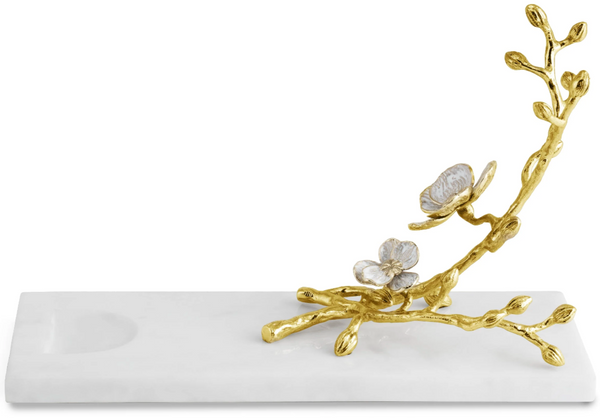 A decorative gold branch with leaves and pearl-like blossoms from the Michael Aram Orchid Wine Rest collection on a white enamel rectangular base.
