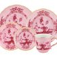 The Oriente Italiano Porpora Dinnerware Collection by Ginori 1735 features pink and white porcelain with floral and lattice motifs, including assorted plates and a gold-trimmed teacup, inspired by Italian elegance.