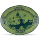 A decorative green ceramic plate from the Ginori 1735 Oriente Italiano Malachite Dinnerware & Decor Collection, featuring dark blue floral and landscape patterns, scalloped edge, and intricate border—ideal for lovers of elegant floral dinnerware.