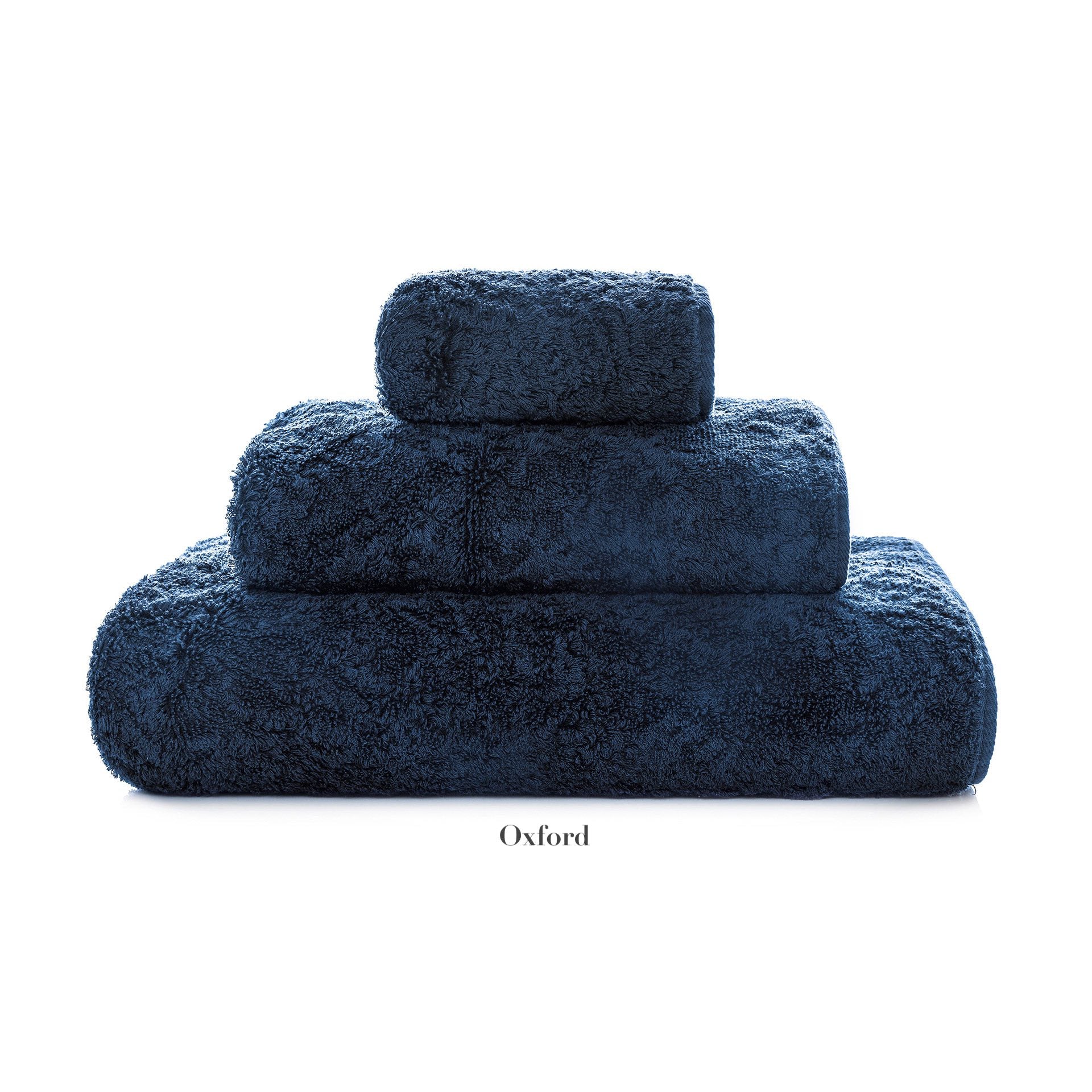 A stack of four neatly folded dark blue Egoist Bath Collection towels by Graccioza, made from high-density textile, rests against a white background.