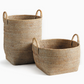 Introducing the Burma Whitewash Rattan Orchard Basket Collection by Napa Home & Garden: two rectangular baskets crafted from natural fibers, each with sturdy handles—one displayed upright and the other positioned horizontally. These versatile woven rattan baskets add stylish organization to any space.